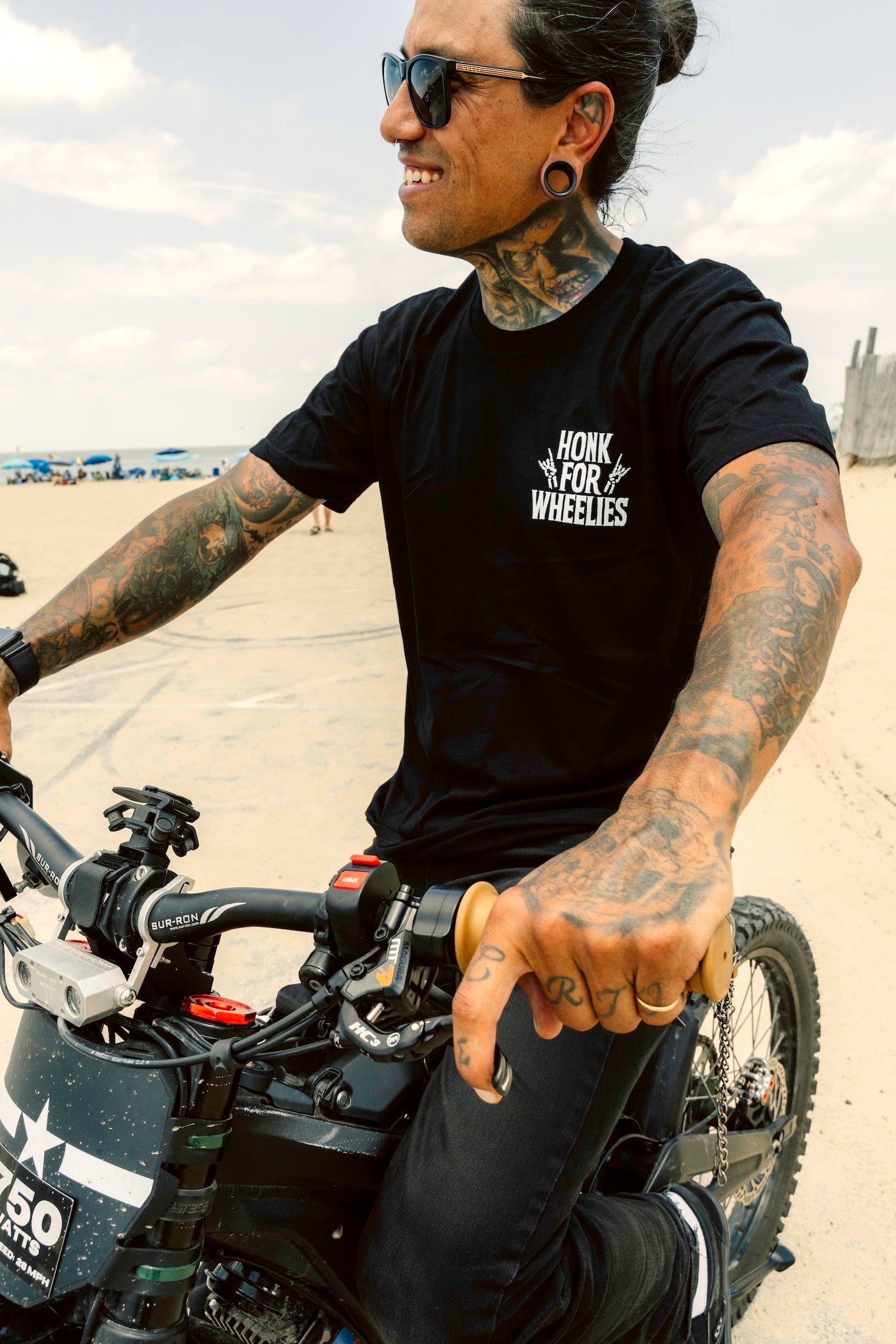 Honk For Wheelies shirt on man with tattoos sitting on a motorcycle.