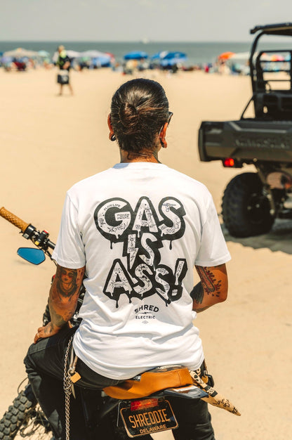 Gas Is Ass white tattoo print electric t-shirt back view on a bike on the beach